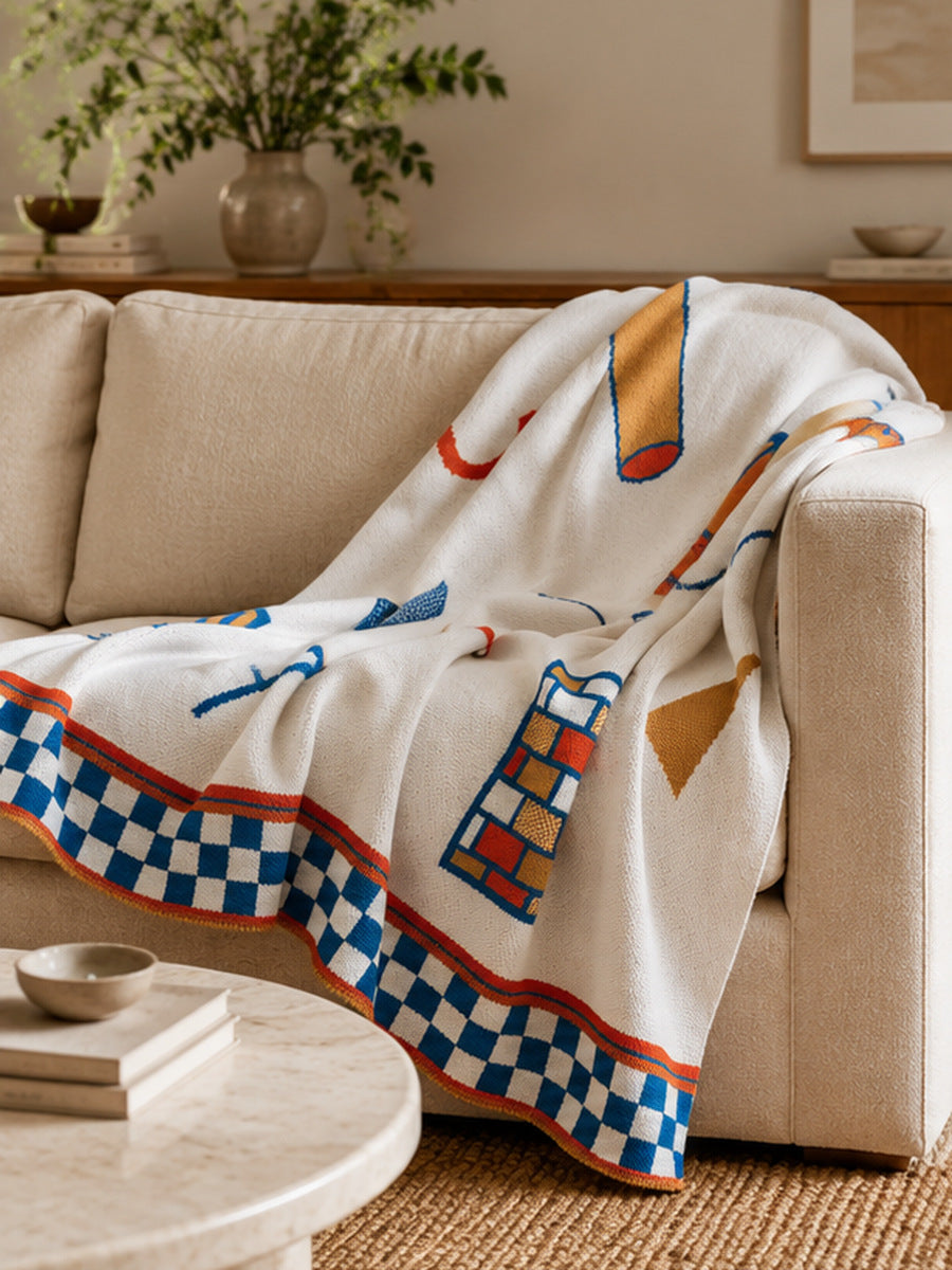 Artist-designed Biquette knit throw blanket draped over a modern sofa